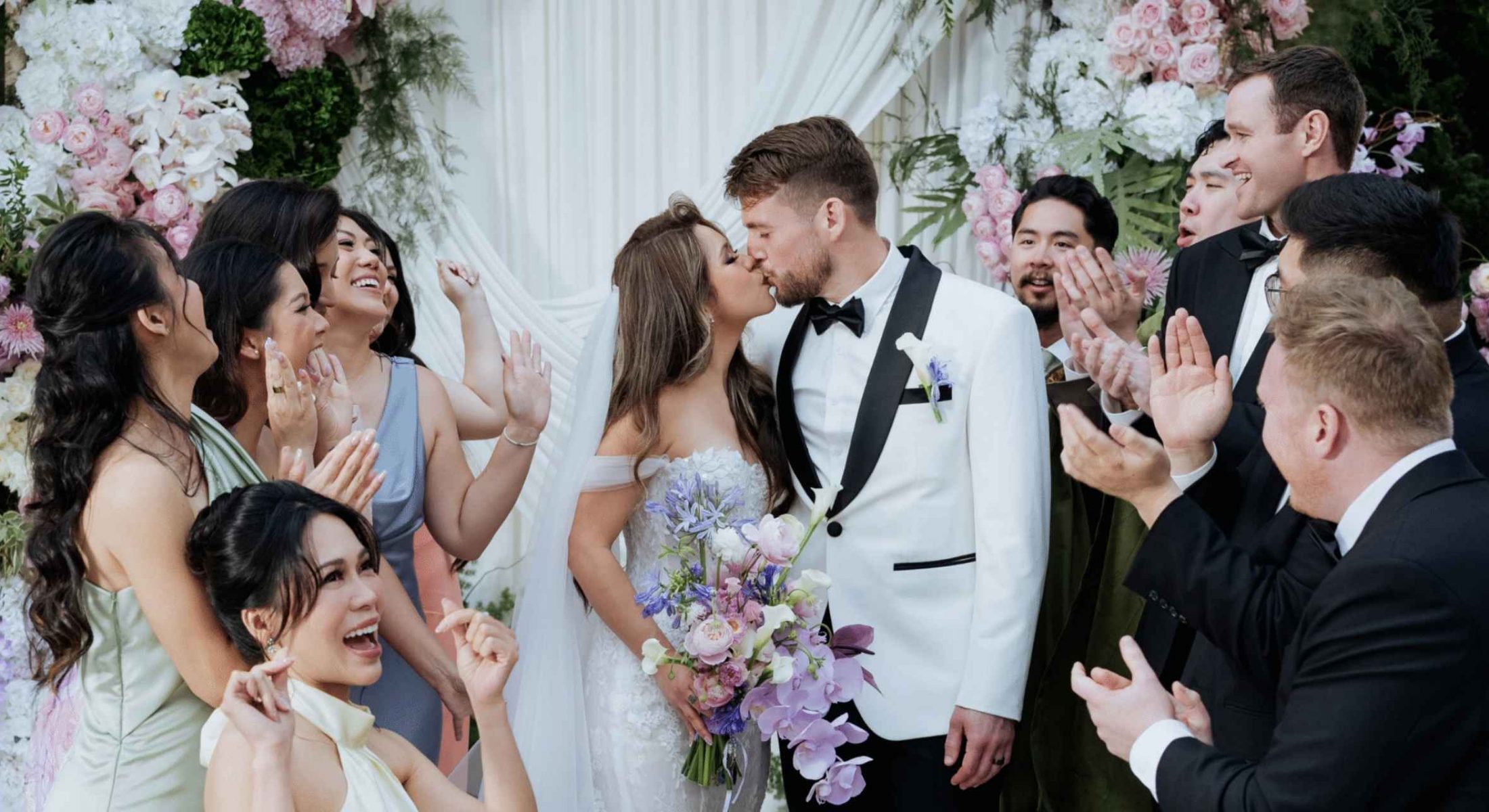 Bride and groom kissing with their wedding party at Grand Mercure Dalat