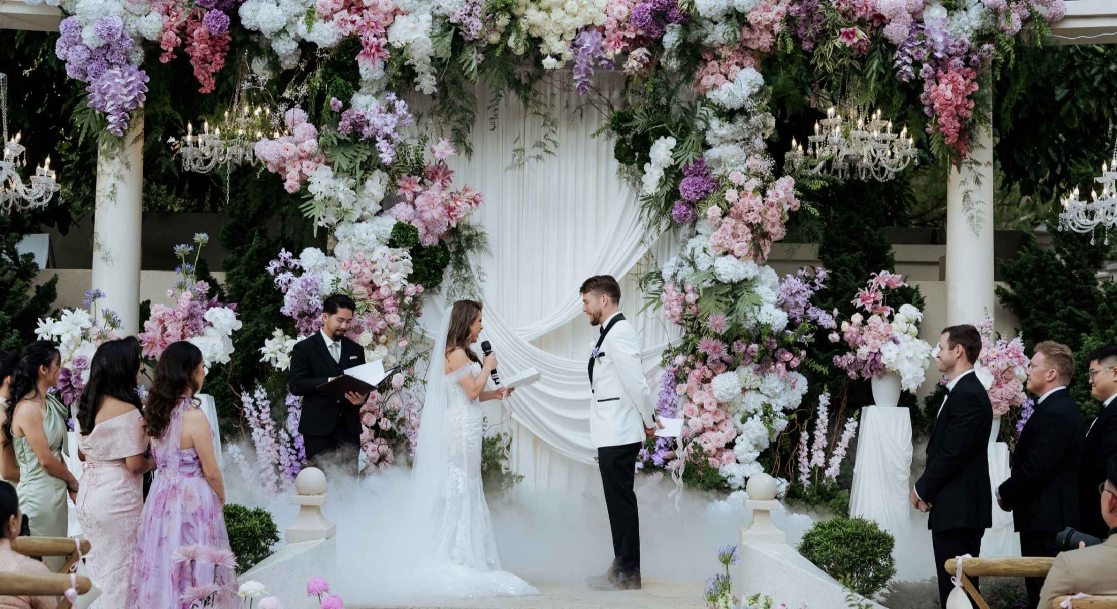 Bride reading her vows beneath a floral arch at Grand Mercure Dalat